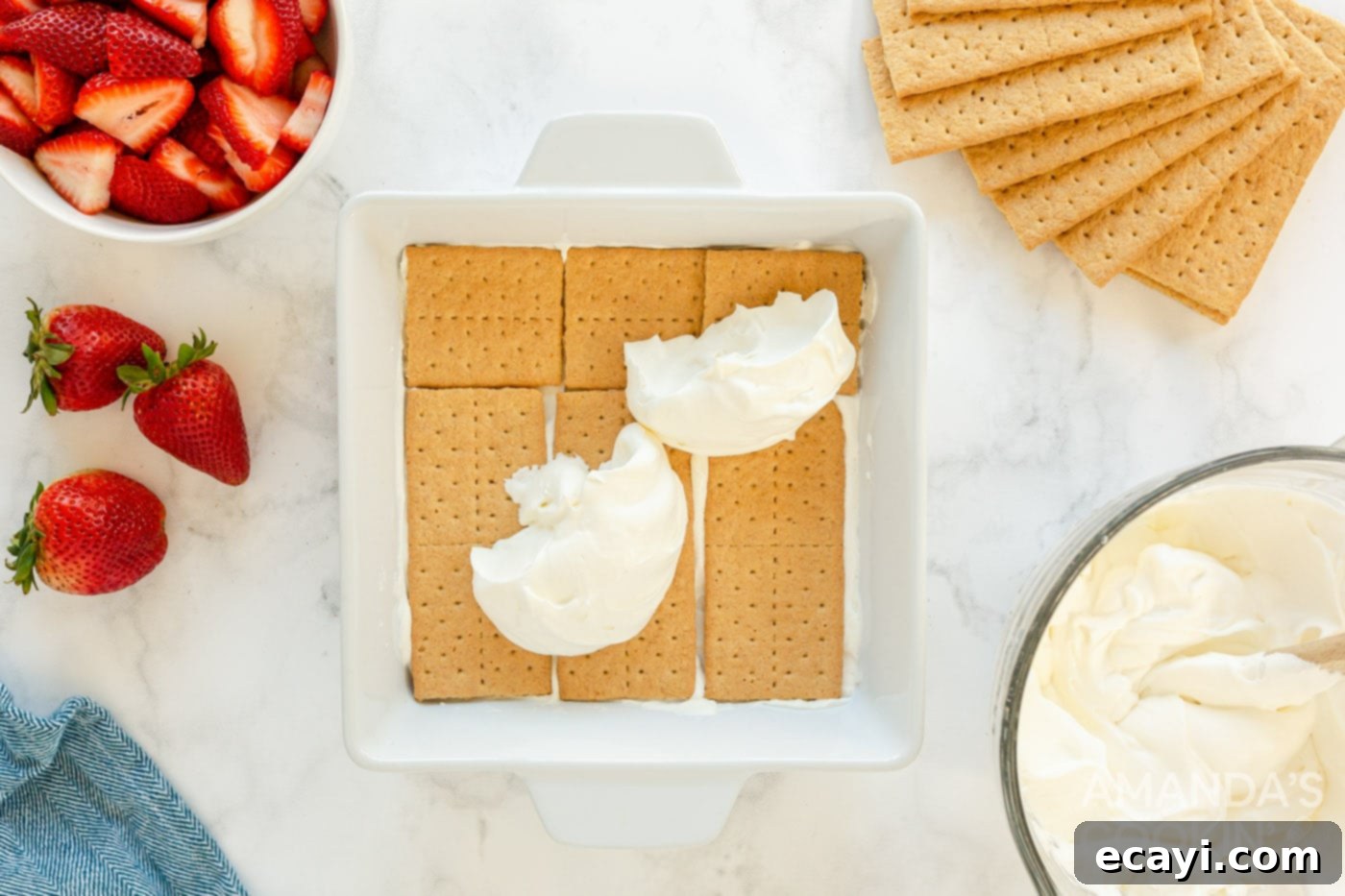 Strawberry Cloud Cake 6 whipped cream being spread on top of graham crackers in a baking dish