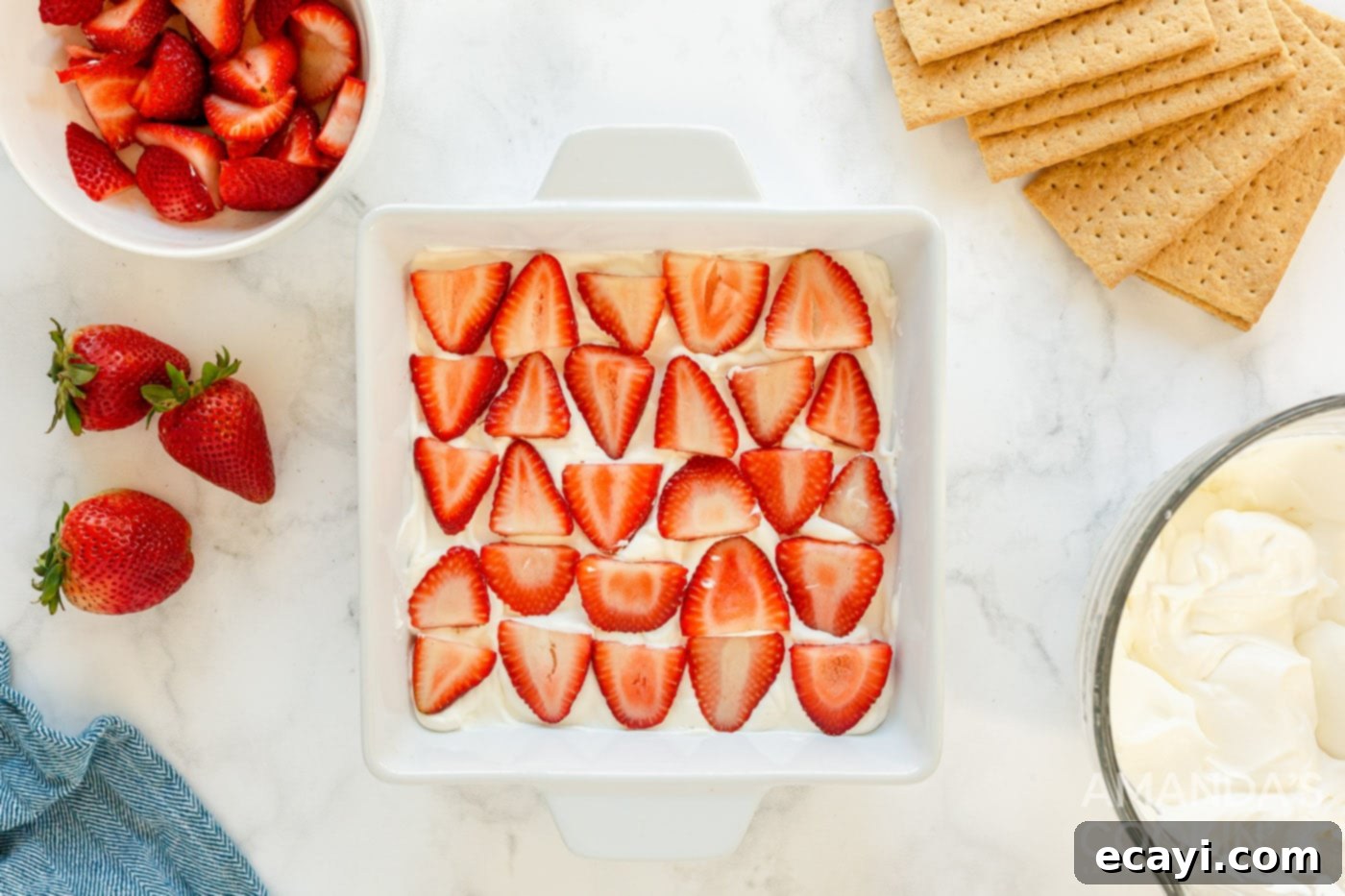 Strawberry Cloud Cake 7 sliced strawberries arranged on top of whipped cream in a baking dish