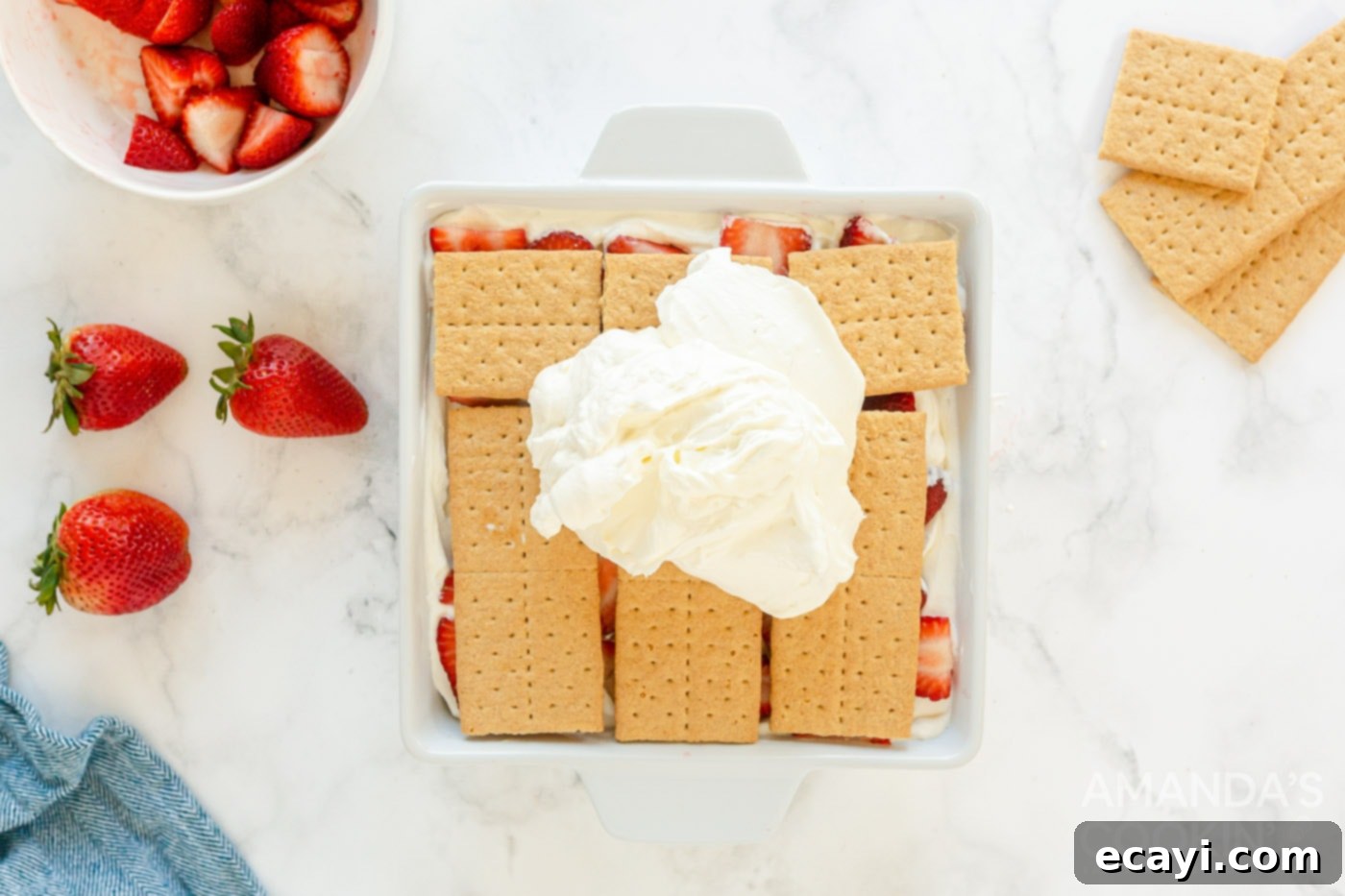 Strawberry Cloud Cake 9 whipped cream being spread over the final layer of graham crackers and strawberries