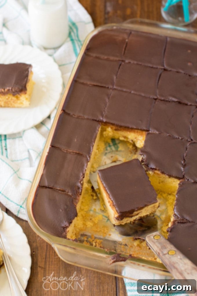 Boston Cream Poke Cake Step 1 overhead photo of chocolate cake in a glass pan with a slice being lifted out