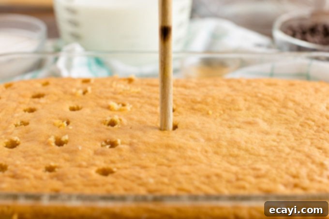 Boston Cream Infusion Dream 3 poking holes in a cake with a wooden spoon