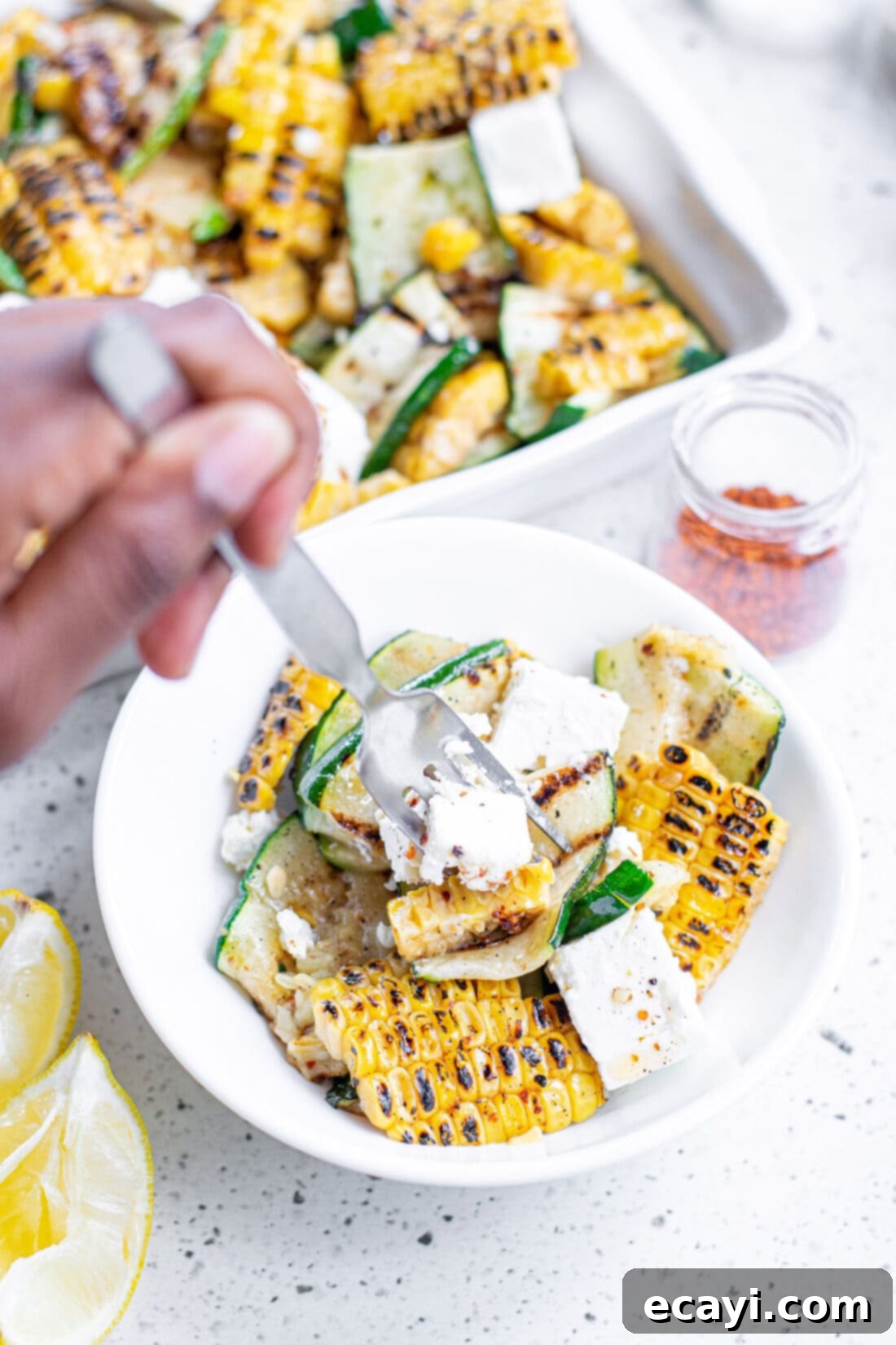 Grilled Corn, Zucchini and Feta Salad 12 A fork taking a spoonful of Grilled Corn & Zucchini Salad with Feta from a bowl, highlighting the fresh, grilled textures.