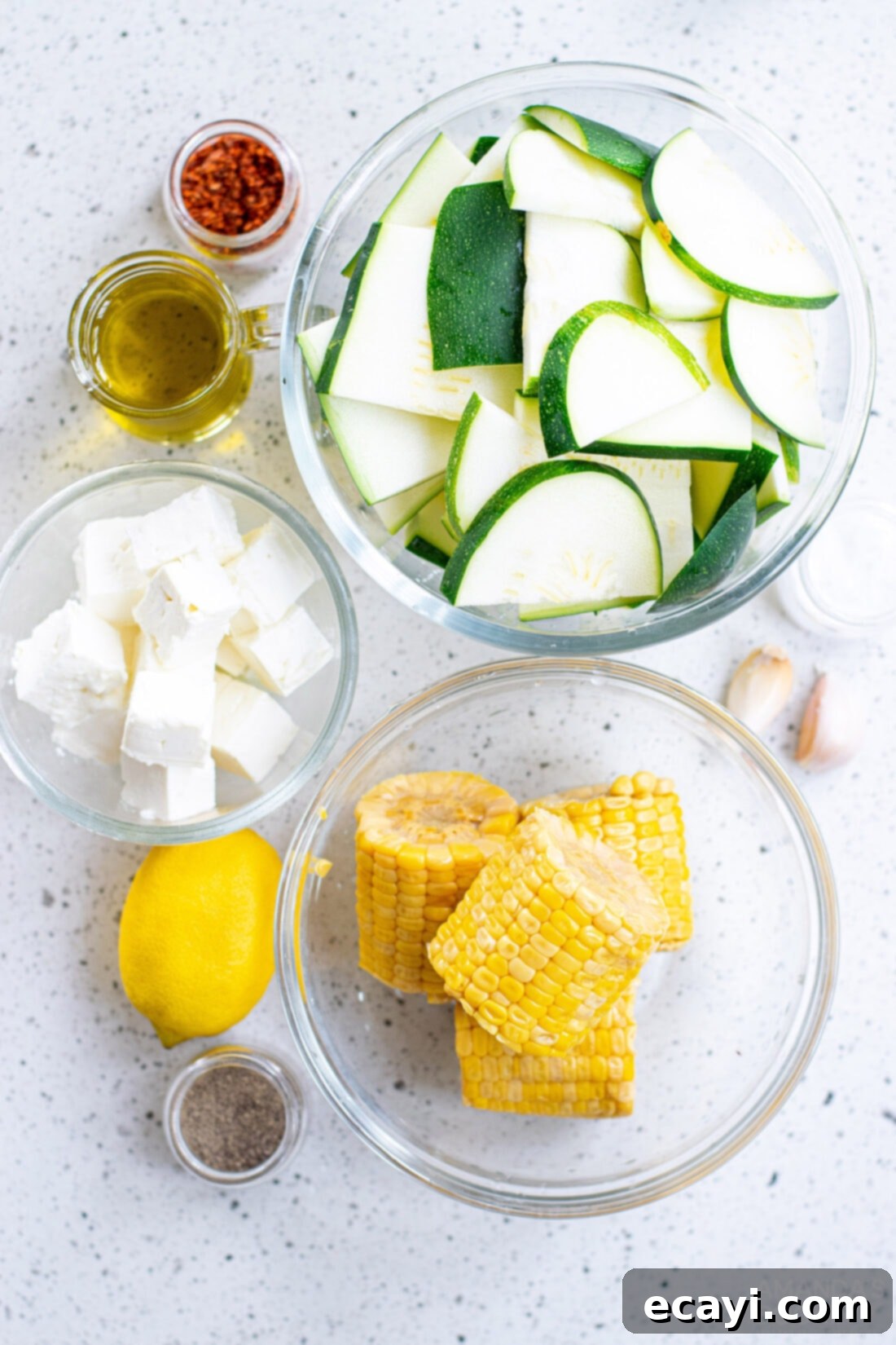 Grilled Corn, Zucchini and Feta Salad 4 A collection of fresh ingredients laid out for making Grilled Corn & Zucchini Salad with Feta, including corn, zucchini, feta, lemon, and spices.