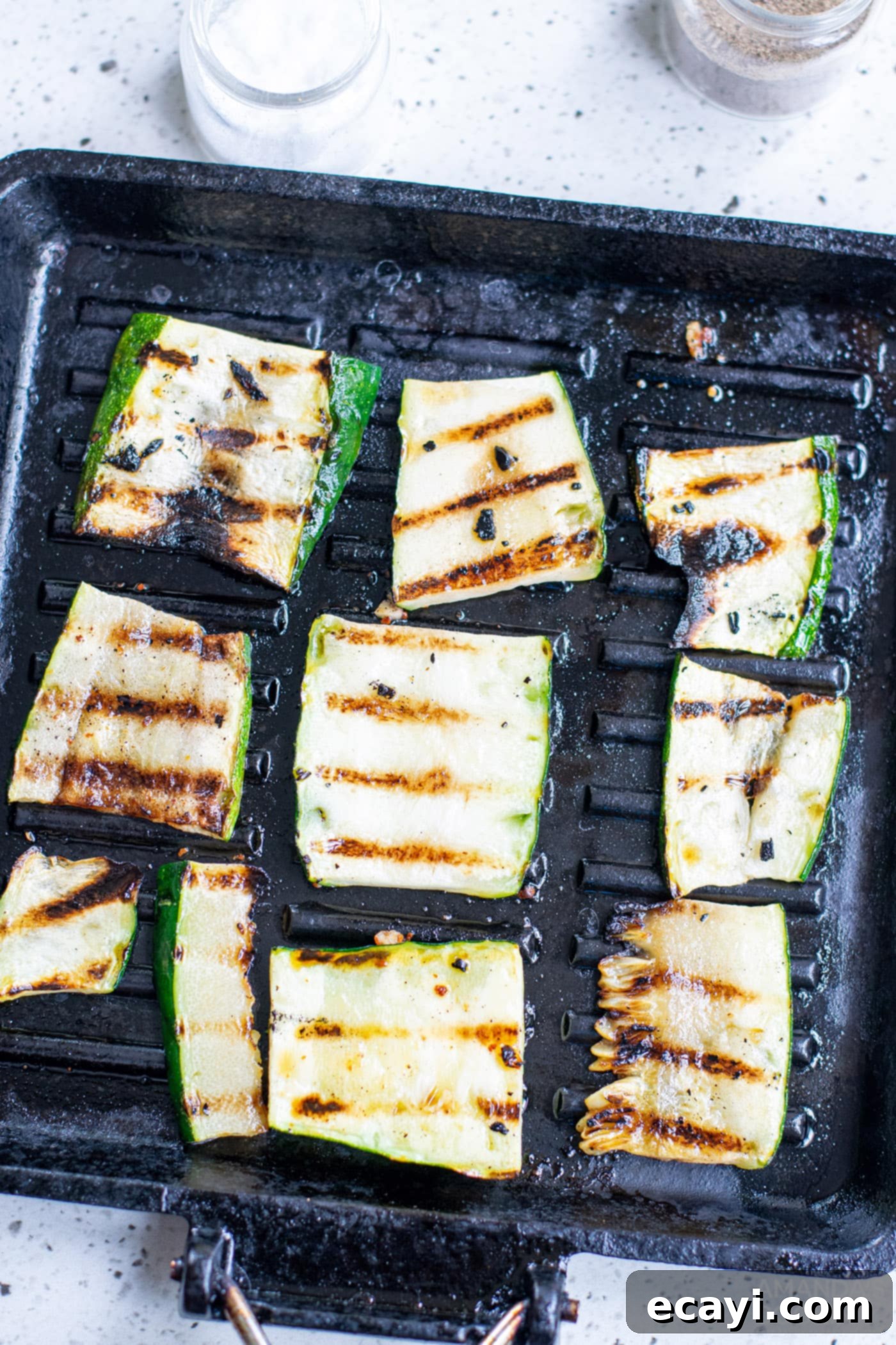 Grilled Corn, Zucchini and Feta Salad 8 Grilled zucchini slices with visible char marks on a hot grill.