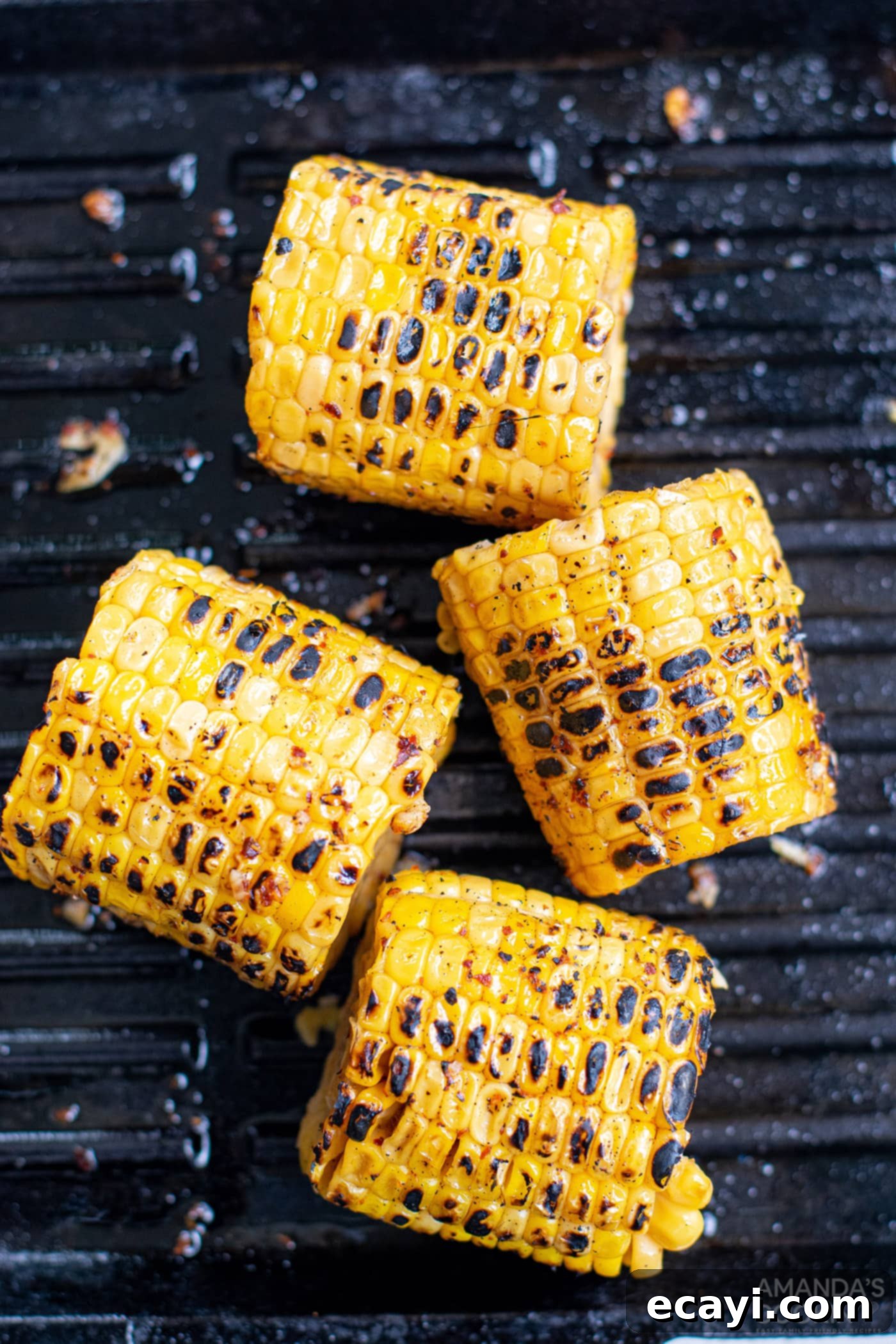 Grilled Corn, Zucchini and Feta Salad 9 Charred corn cobs cooking on a hot grill, showing smoky flavor development.