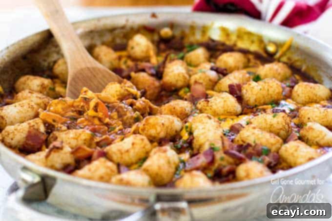 The BBQ Chicken Tater Tot Skillet cooking in one pan. A close-up shot of the cooking process showing the chicken and tater tots in the skillet.