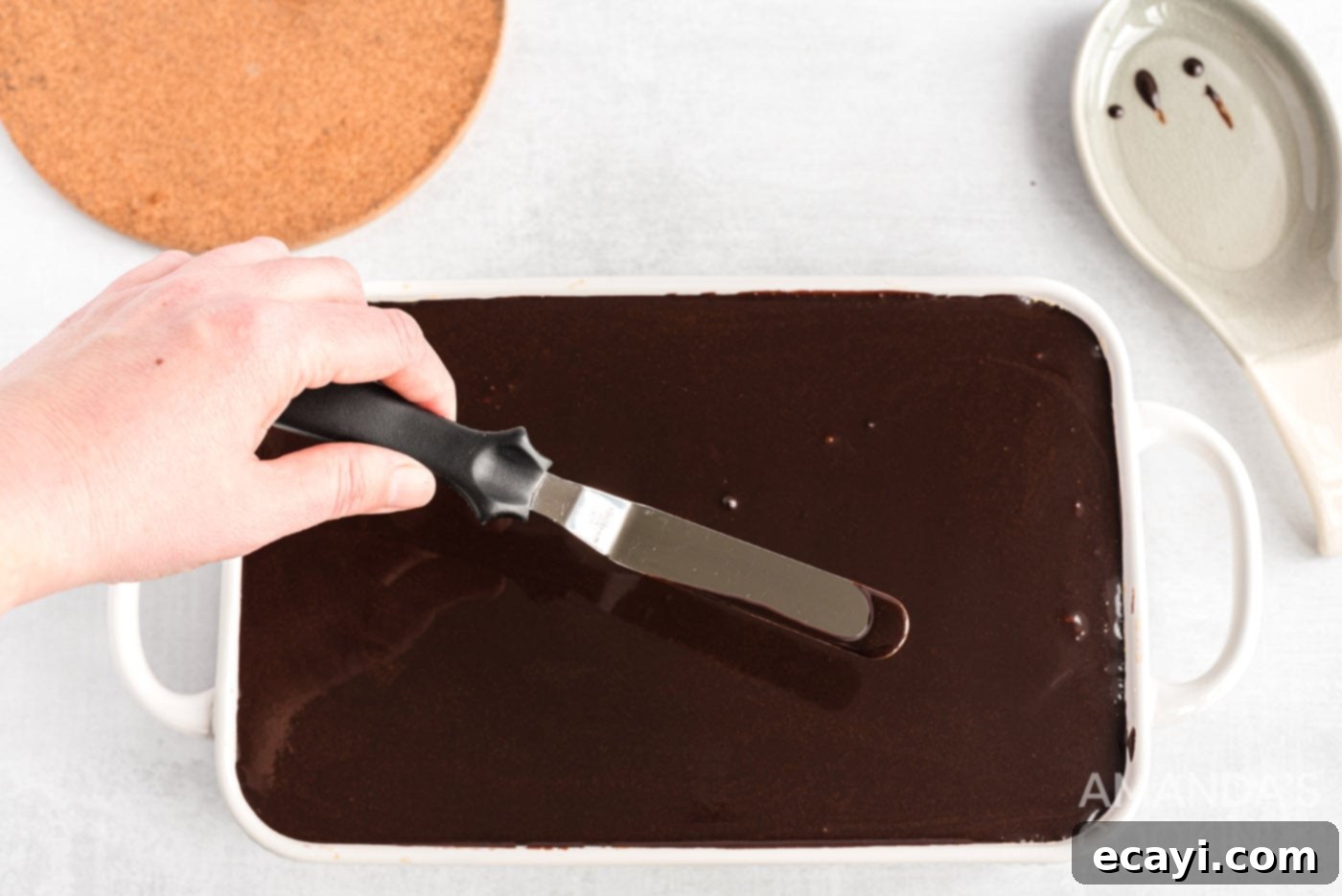 Decadent Eclair Delight 14 spreading chocolate ganache smoothly over the cake with an icing spatula