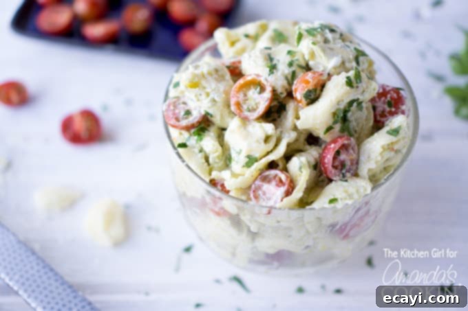 Zesty Pesto Tortellini Salad 4 Delicious and creamy Tortellini Pesto Pasta Salad in a white bowl, garnished with fresh herbs