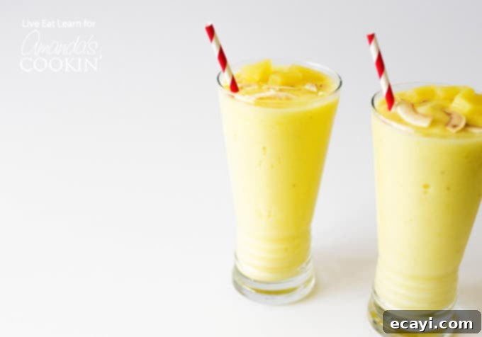 Pina Colada Paradise Smoothie 4 Top-down view of two Pina Colada Smoothies in glasses, garnished with pineapple wedges.