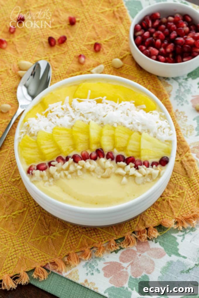This refreshing tropical smoothie bowl is bursting with flavor and reminds me of a bowl of sunshine! This smoothie bowl is perfect for summer. #tropical #smoothie #smoothiebowl #breakfast #fruit #dairyfree #mango #peach #coconut A vibrant tropical smoothie bowl on an orange cloth, garnished with fresh fruit and coconut
