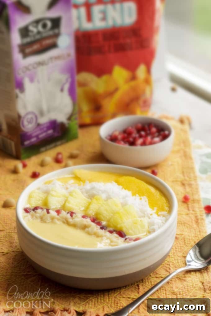 This refreshing tropical smoothie bowl is bursting with flavor and reminds me of a bowl of sunshine! This smoothie bowl is perfect for summer. #tropical #smoothie #smoothiebowl #breakfast #fruit #dairyfree #mango #peach #coconut Close-up of a colorful smoothie bowl on an orange fabric, showing various tropical fruit toppings