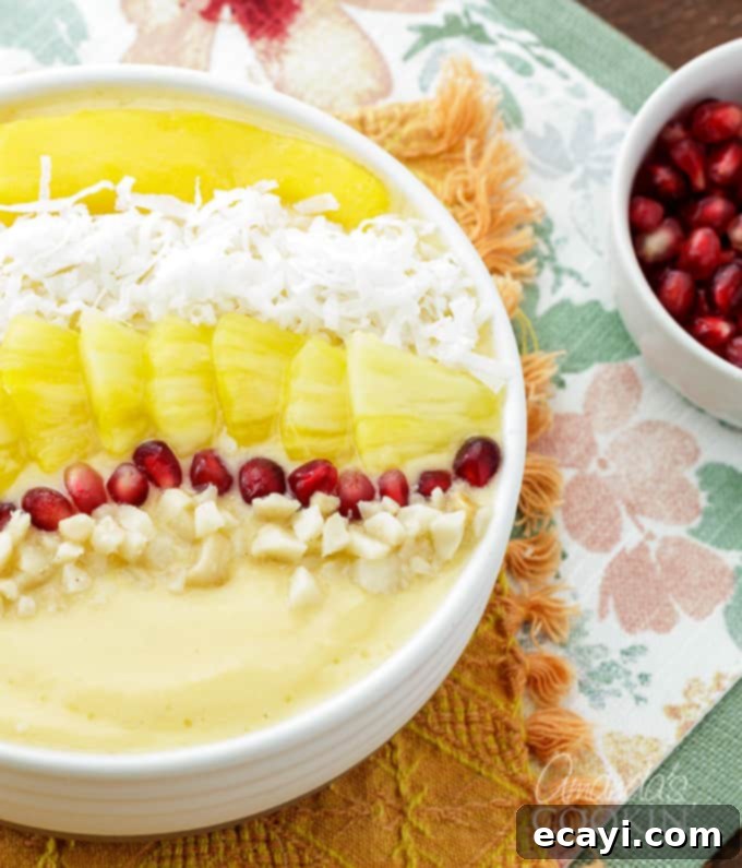 This refreshing tropical smoothie bowl is bursting with flavor and reminds me of a bowl of sunshine! This smoothie bowl is perfect for summer. #tropical #smoothie #smoothiebowl #breakfast #fruit #dairyfree #mango #peach #coconut Beautifully arranged Tropical Smoothie Bowl with all its vibrant toppings