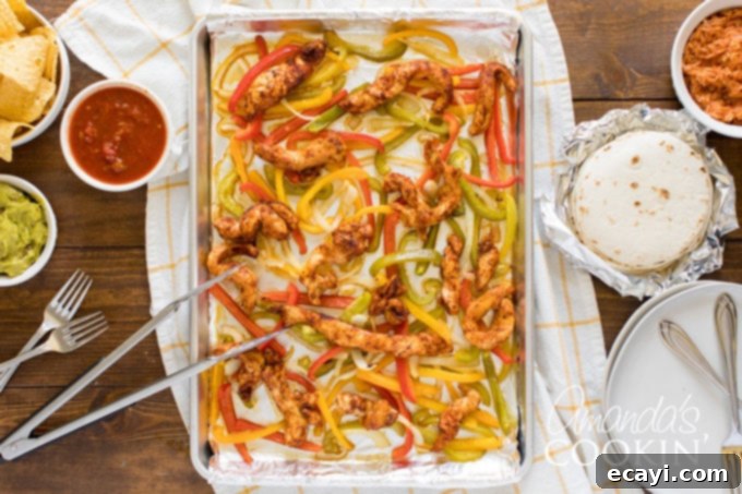 One-Pan Chicken Fajitas 3 Uncooked fajita ingredients, including sliced chicken, bell peppers, and onions, on a sheet pan