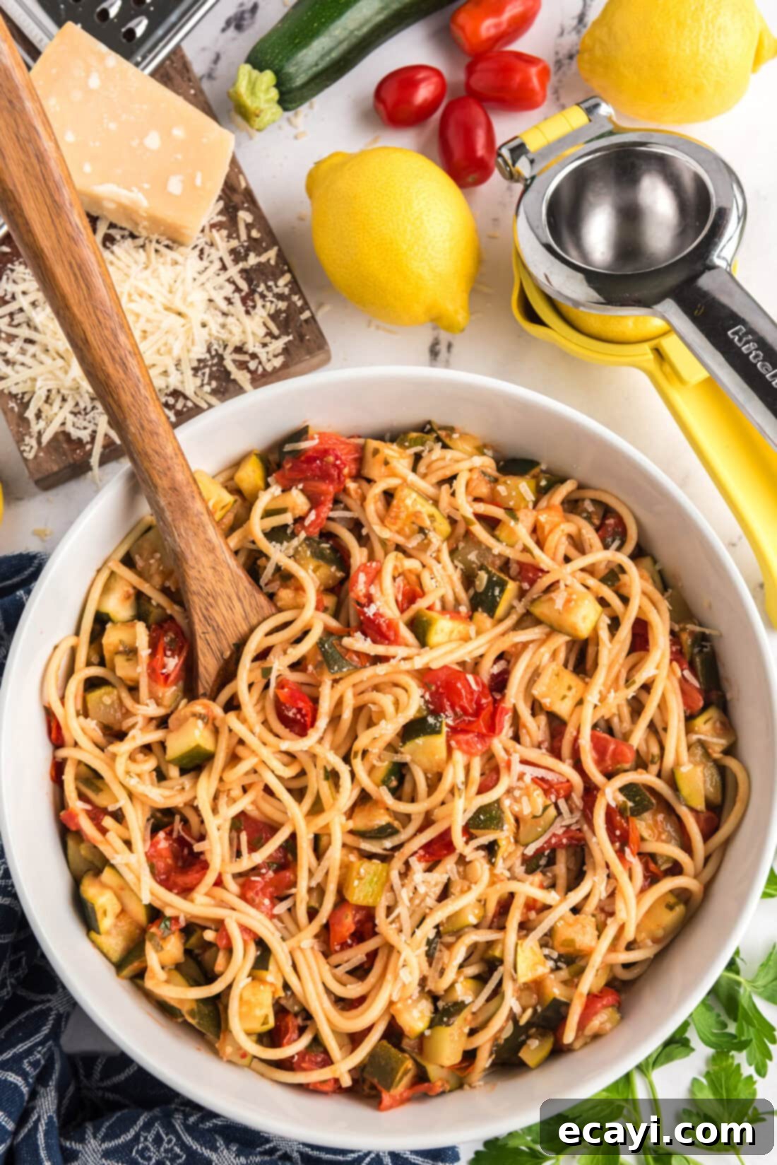 Summer Zucchini Tomato Pasta 11 A bowl of Simple Zucchini Tomato Pasta with a spoon, generously garnished with fresh Parmesan cheese, ready to be enjoyed.