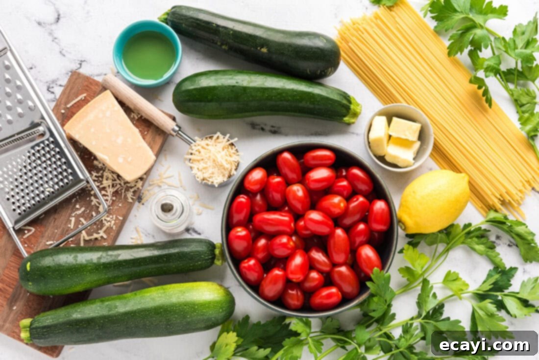 Summer Zucchini Tomato Pasta 4 Fresh ingredients laid out for Simple Zucchini Tomato Pasta: vibrant green zucchini, ripe red grape tomatoes, fresh parsley, a lemon, and uncooked pasta.