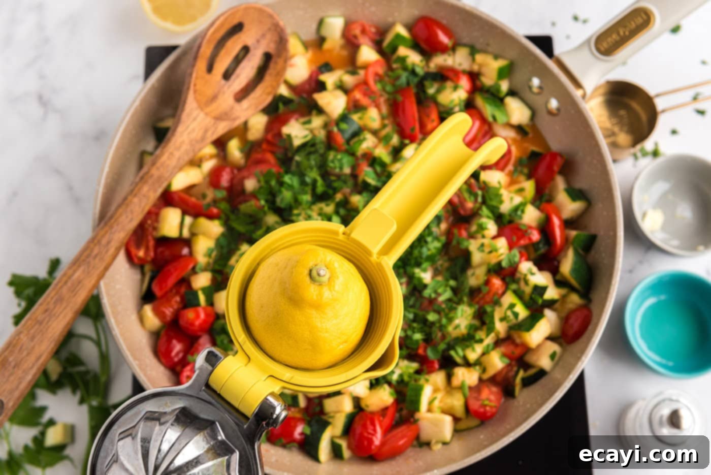 Summer Zucchini Tomato Pasta 7 Fresh lemon juice being squeezed into a pan of sautéed zucchini and tomatoes, alongside chopped parsley.