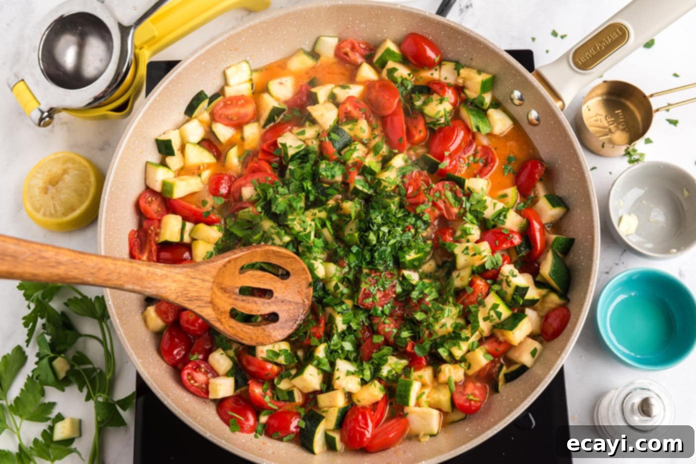 Summer Zucchini Tomato Pasta 8 A wooden spoon mixing zucchini, tomatoes, and parsley in a skillet, ensuring the fresh ingredients are well distributed.