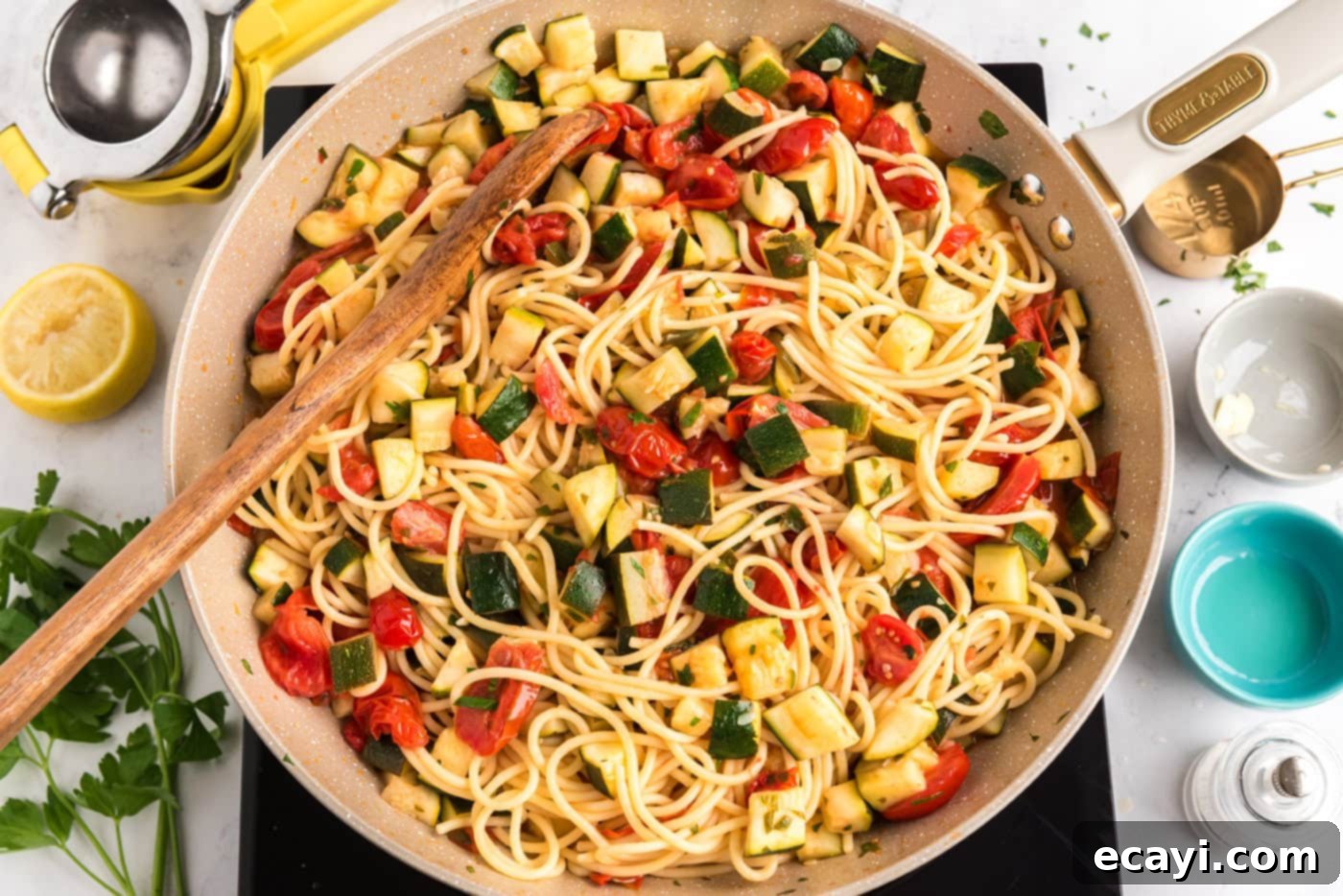 Summer Zucchini Tomato Pasta 10 Zucchini tomato pasta being mixed in a skillet with a wooden spoon, showcasing the finished, well-combined dish.