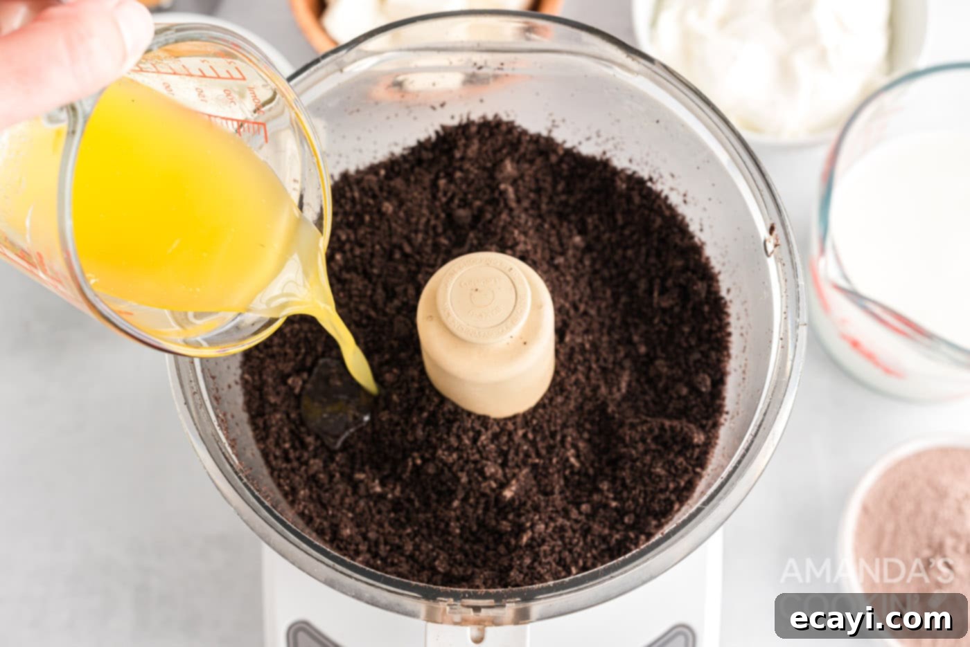 Decadent Chocolate Peanut Butter Stack 5 pouring melted butter into oreos crumb in a food processor
