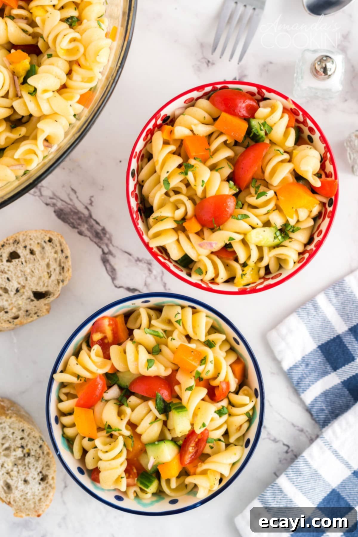 Minimal dressing ingredients and maximum fresh vegetables, this summer pasta salad will be the hit of your summer parties and holiday get togethers. Two bowls of vibrant summer pasta salad, garnished with fresh basil, on a table with a blue and white tea towel