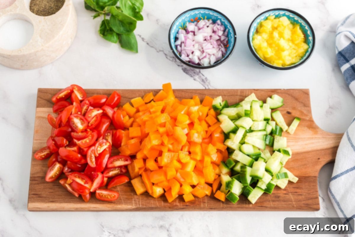 Refreshing Summer Pasta Salad 3 Assortment of freshly chopped vegetables, including bell peppers, cucumbers, and red onions, on a cutting board
