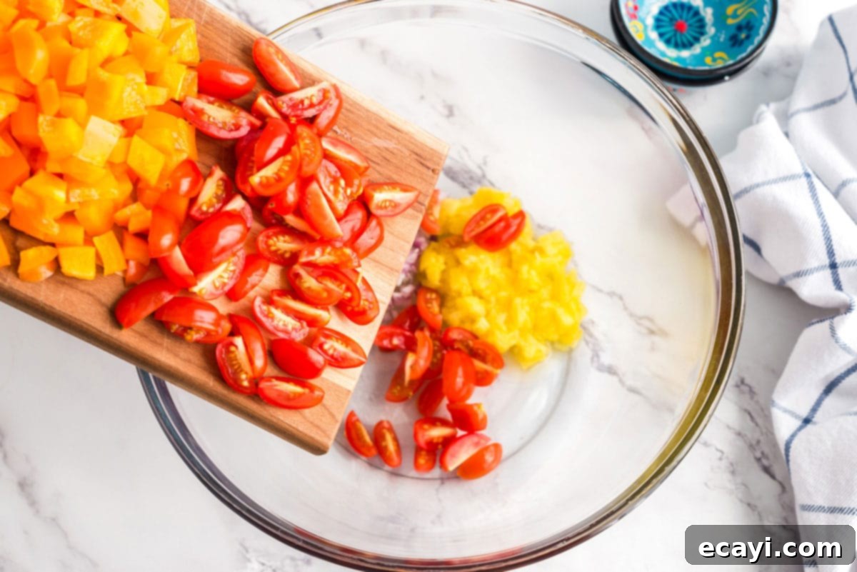 Refreshing Summer Pasta Salad 4 Adding sliced cherry tomatoes to a large serving bowl filled with pasta and other chopped vegetables