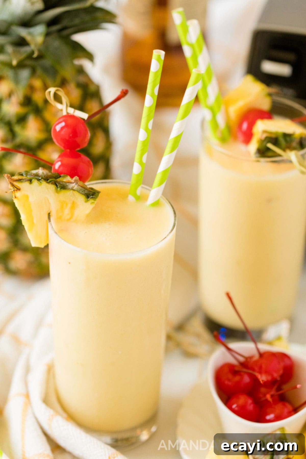 With only 3 ingredients, this pineapple rum slush is one of our favorite frozen rum drinks! A quick cocktail that's perfect for a crowd on a hot summer day. Two glasses of pineapple rum slush with a blender in the background