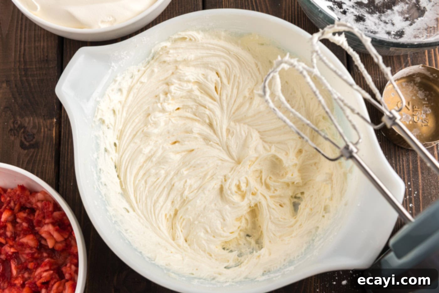 Blush Berry Bliss 7 Close-up of a creamy cream cheese and butter mixture being beaten by an electric mixer whisk, illustrating the smooth consistency.
