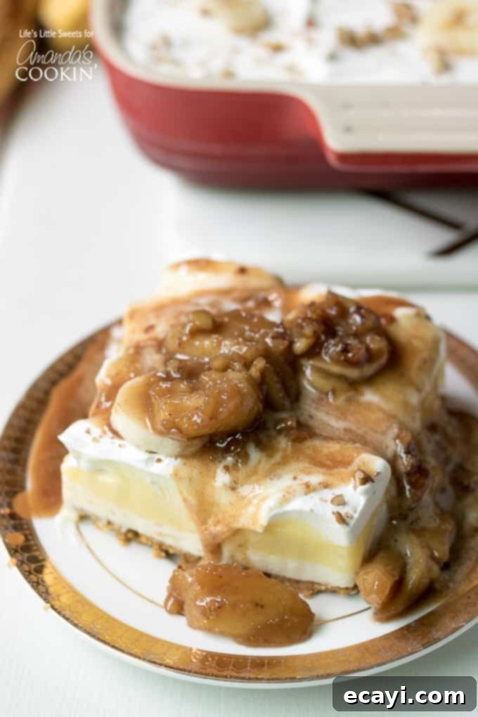 Decadent Bananas Foster sauce flowing over a slice of Banana Cream Lush. Layered banana dessert with warm caramel banana fosters sauce drizzled on top