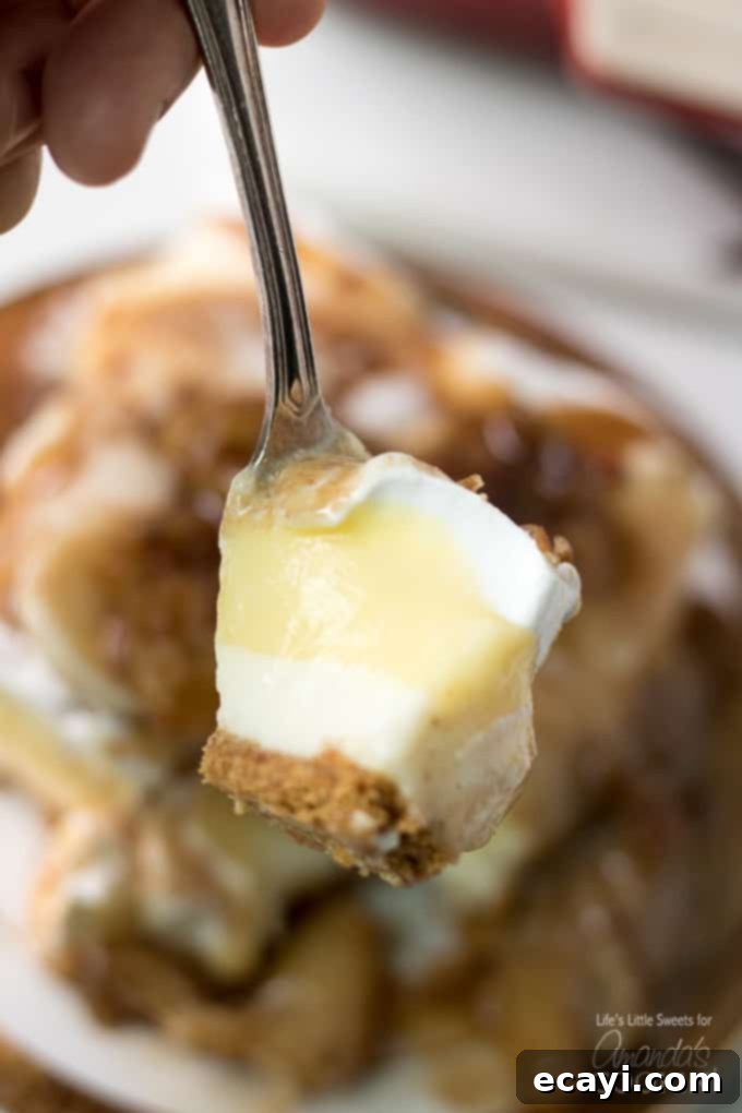 A fork showcasing the intricate layers and inviting texture of the dessert. A fork holding a portion of banana cream lush layered dessert