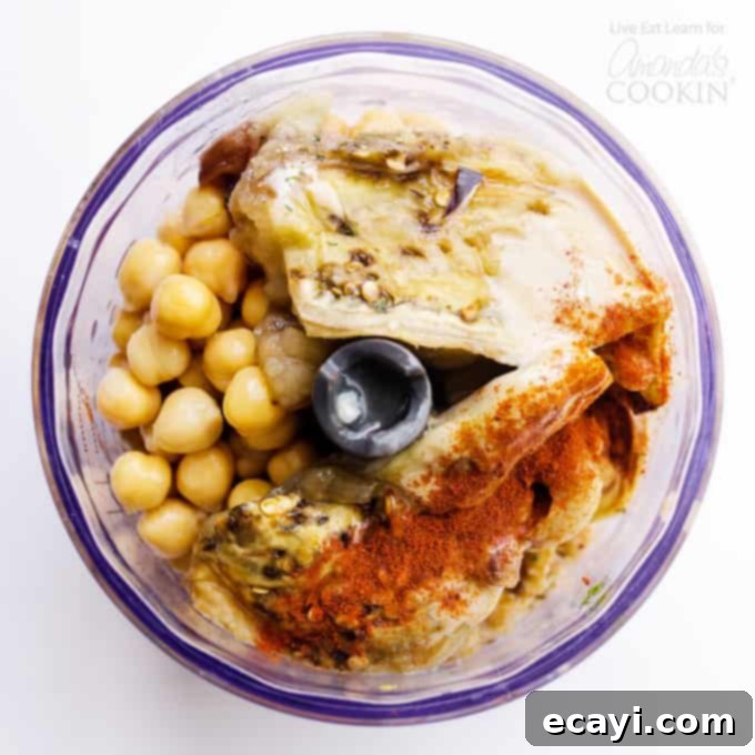 Crafting this delightful Baba Ganoush Hummus involves combining roasted eggplant with classic hummus ingredients for a rich, flavorful, and healthy dip. #eggplant #hummus #vegetarian #chickpeas #healthyrecipes #dips #appetizers Ingredients for Baba Ganoush Hummus being prepared in a food processor