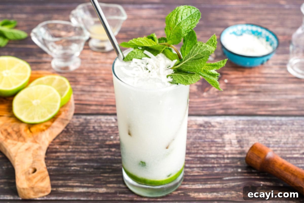 This refreshing Coconut Mojito is made with fresh cooling mint, coconut rum, coconut cream and club soda. A delicious and tropical cocktail for summer! glass of coconut rum mojito garnished with mint and coconut flakes