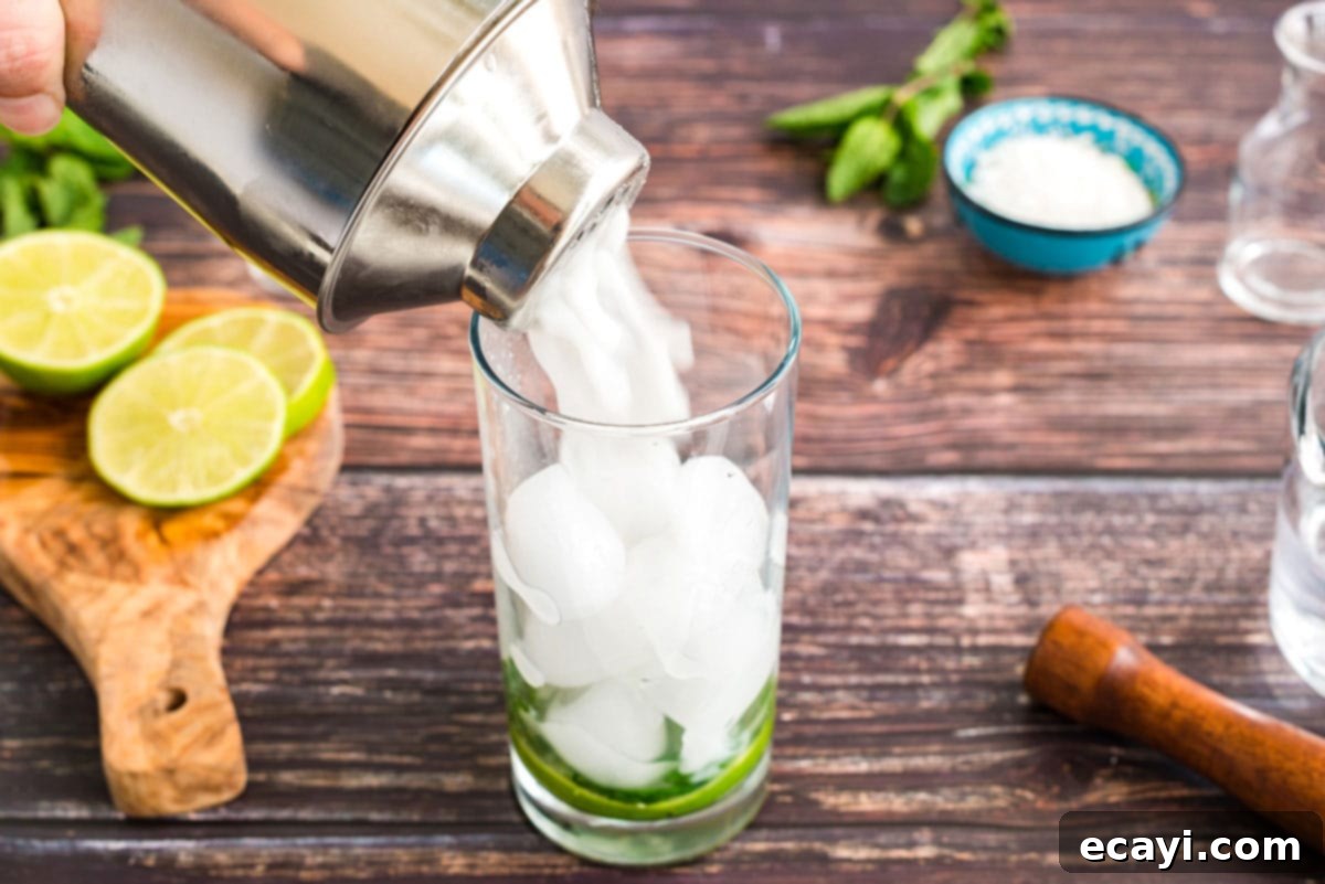 Island Coconut Dream 7 straining coconut mojito into a glass