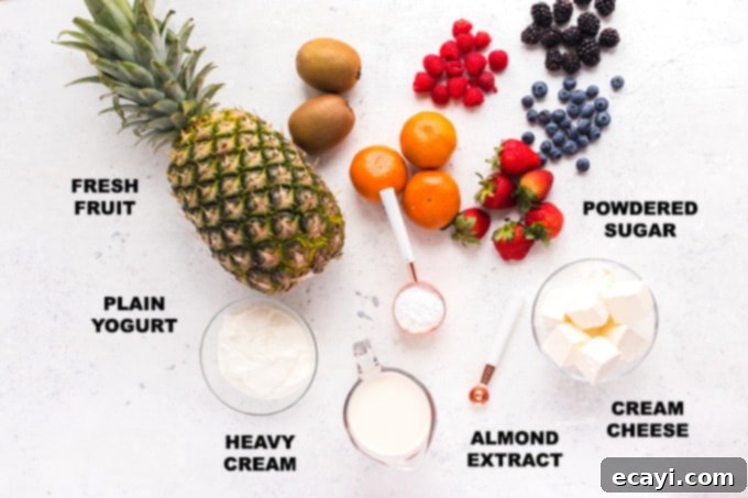 Luscious Cream Cheese Fruit Dip 2 Individual ingredients neatly laid out on a clean counter: a block of cream cheese, a tub of Greek yogurt, a measuring cup of powdered sugar, a bottle of almond extract, and a container of heavy cream.
