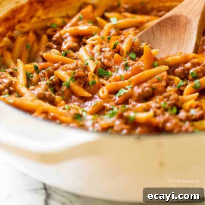 A twist on a classic, this one pot sloppy joe pasta is easy to make and has everything you love about sloppy joes with no hamburger buns required. #sloppyjoe #pastarecipes #comfortfood #onepotmeals pan of sloppy joe pasta with a wooden spoon
