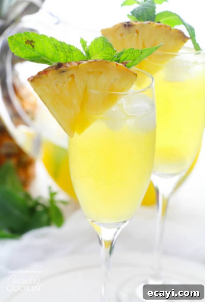 This Pineapple Prosecco Punch is bursting with pineapple, white rum, mango juice, Prosecco and a hint of mint. Perfect for sipping and relaxing! #cocktail #brunch #summercocktails #summerdrinks #partydrinks #prosecco #pineapple #wine #rum #brunchcocktail Beautiful pitcher filled with vibrant Pineapple Prosecco Punch, garnished with fresh mint and pineapple slices, ready for serving.