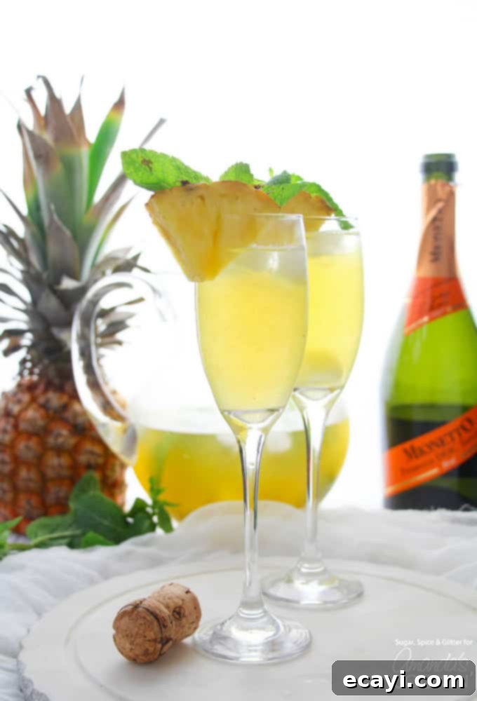 This Pineapple Prosecco Punch is bursting with pineapple, white rum, mango juice, Prosecco and a hint of mint. Perfect for sipping and relaxing! #cocktail #brunch #summercocktails #summerdrinks #partydrinks #prosecco #pineapple #wine #rum #brunchcocktail Two champagne flutes filled with sparkling Pineapple Prosecco Punch, adorned with fresh pineapple wedges and mint leaves on a light background.