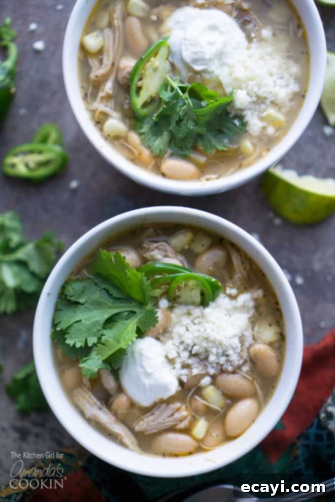 This easy white chicken chili recipe is perfect for your slow cooker, offering simple prep and incredibly savory, spicy flavors. #chickenrecipes #chicken #chili #whitechickenchili #crockpot #slowcooker #crockpotrecipes #crockpotsoup #soup #souprecipes Delicious white chicken chili recipe in a rustic bowl, garnished with cilantro and sour cream