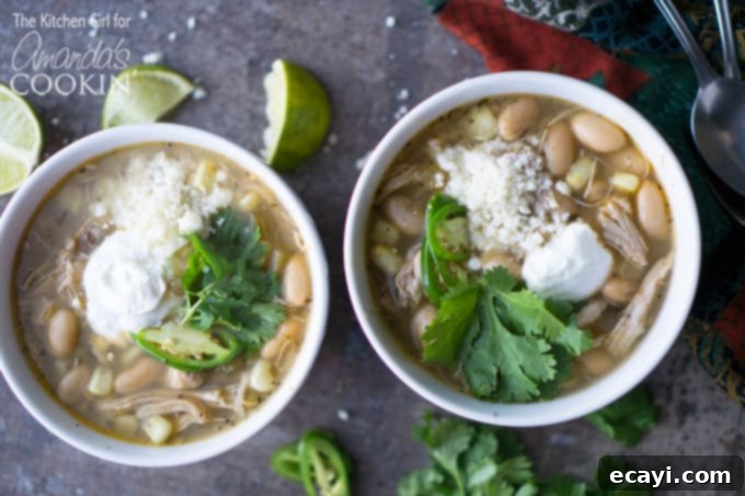 Serve this delicious white chicken chili with your favorite toppings for a cozy and satisfying meal. #chickenrecipes #chicken #chili #whitechickenchili #crockpot #slowcooker #crockpotrecipes #crockpotsoup #soup #souprecipes Three bowls of white chicken chili on a wooden table, with fresh lime wedges and cilantro garnish