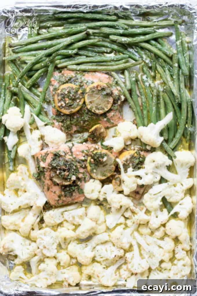 A super easy and flavorful 30-minute sheet pan salmon dinner! Close-up of the Sheet Pan Salmon Dinner with perfectly roasted green beans and cauliflower, showcasing the golden-brown salmon fillet and vibrant lemon slices.