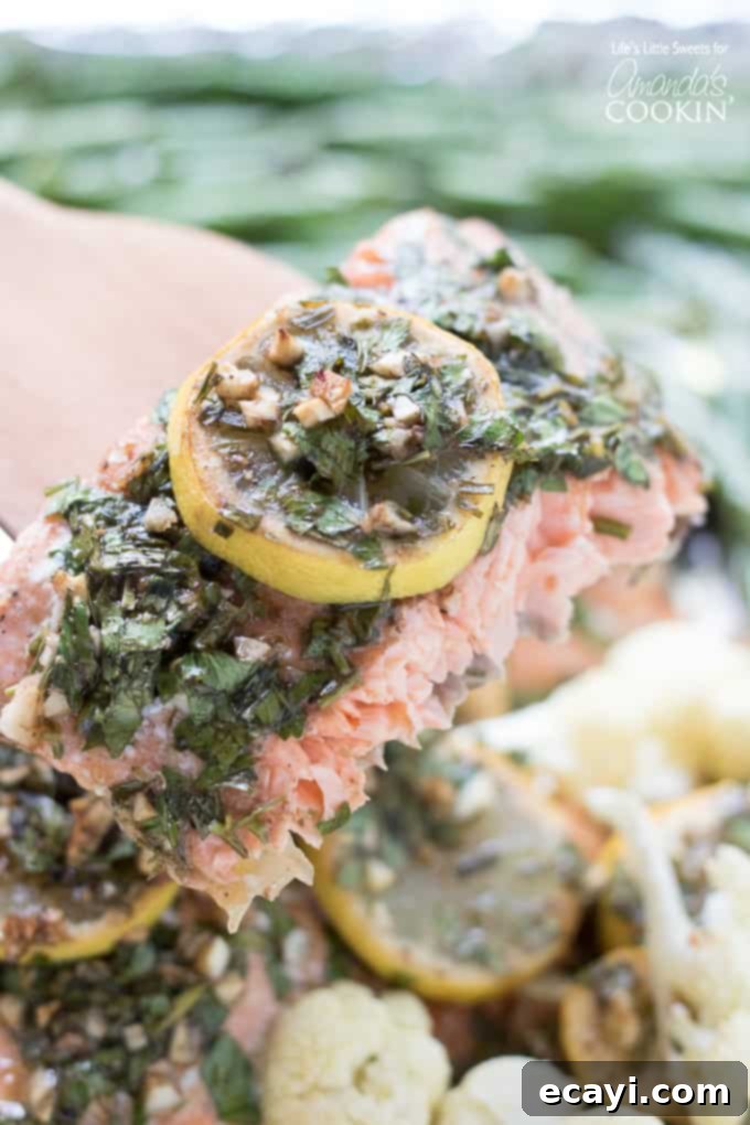 One-Pan Salmon Feast 4 Cooked sheet pan salmon fillet adorned with lemon slices and fresh tarragon sprigs, a close-up highlighting its delicious texture.