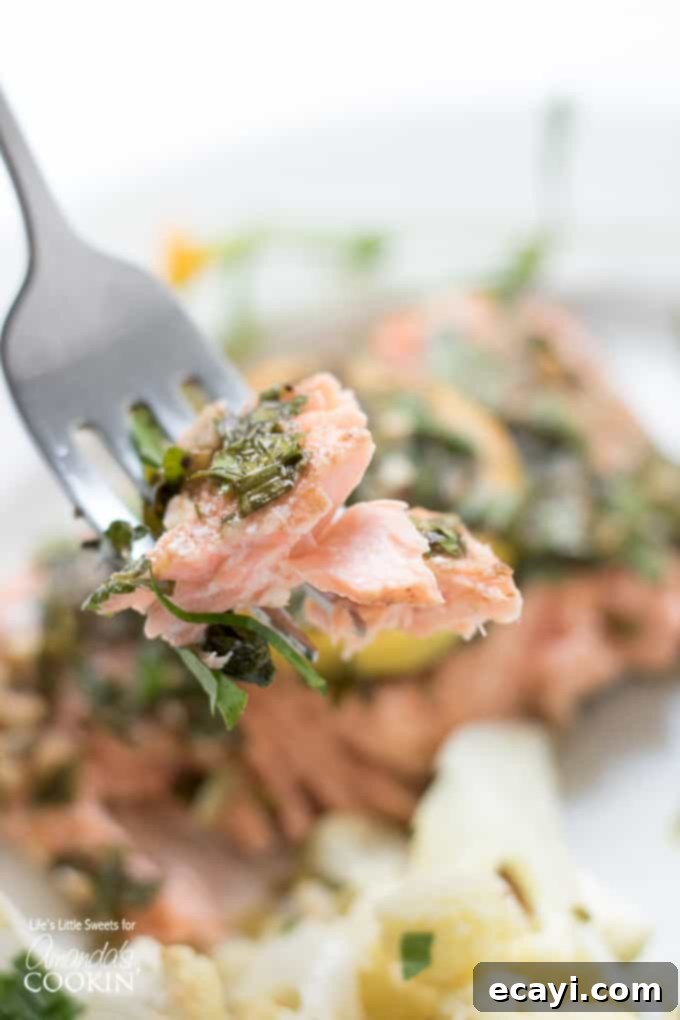 One-Pan Salmon Feast 5 Close-up of a fork flaking perfectly cooked salmon, emphasizing the tender, moist texture of the fish from the sheet pan dinner.