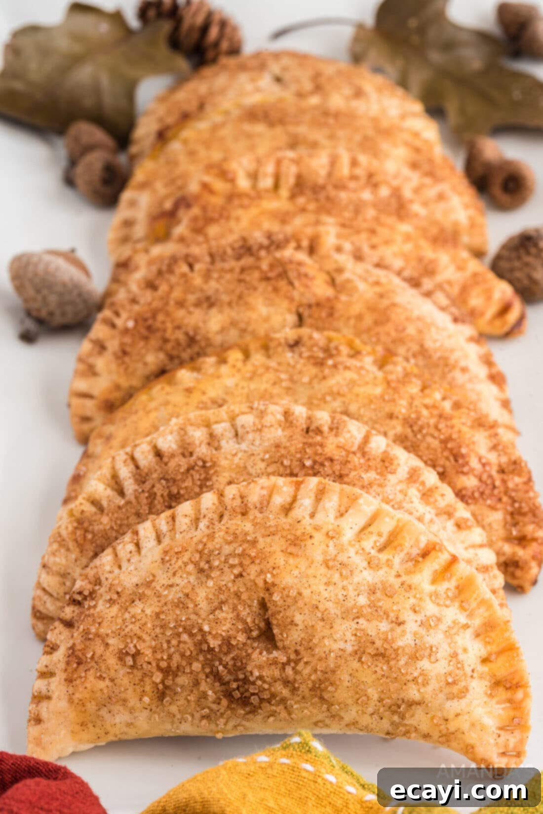 Flaky Pumpkin Turnovers 12 Several golden brown Pumpkin Hand Pies artfully arranged on a white plate, ready for serving.