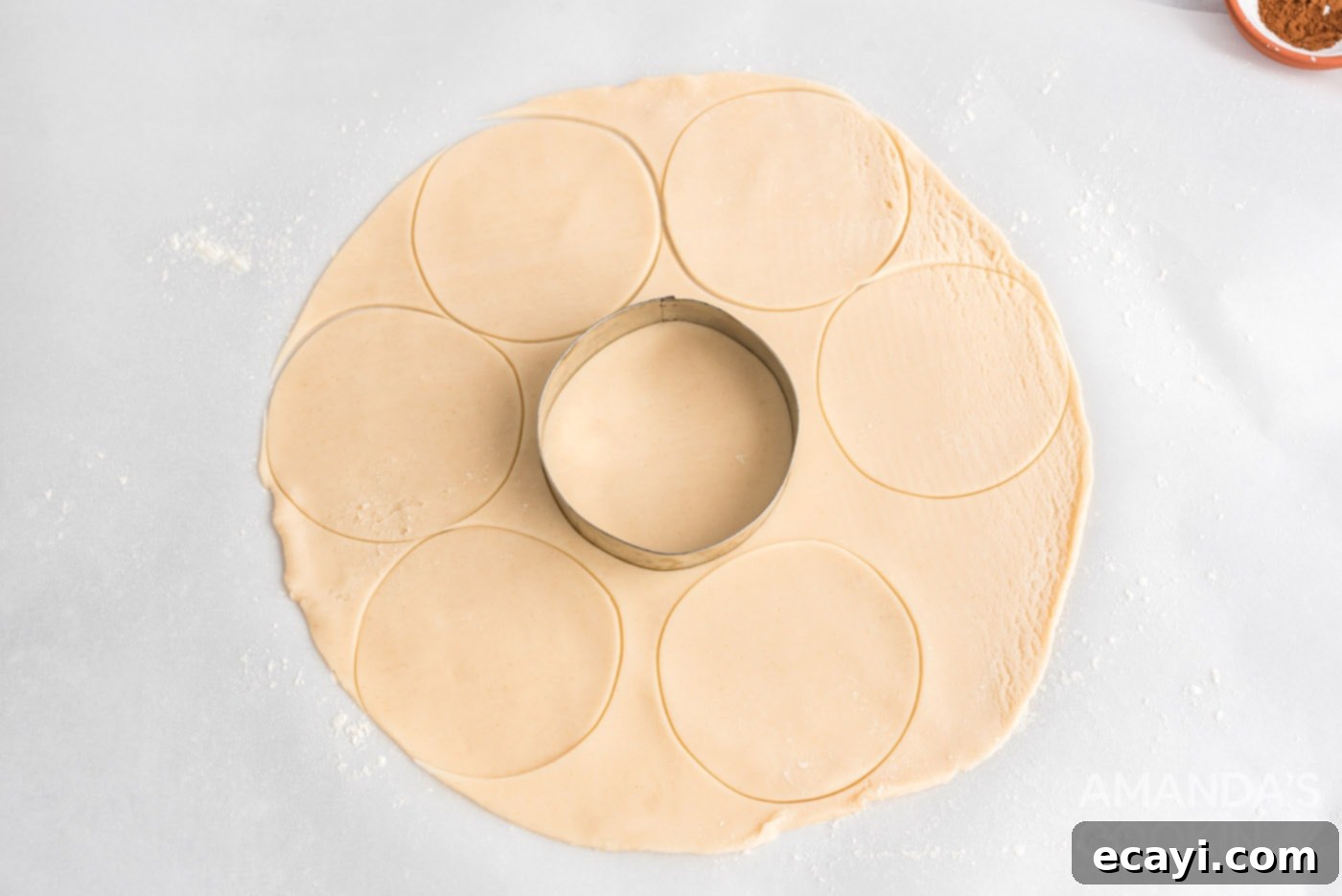 Flaky Pumpkin Turnovers 7 A biscuit cutter pressing into rolled-out pie crust dough to create perfect circles for hand pies.
