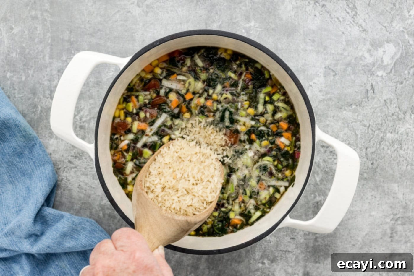 Hearty Veggie Rice Soup 9 adding uncooked rice to vegetable soup in a pot, ready to simmer