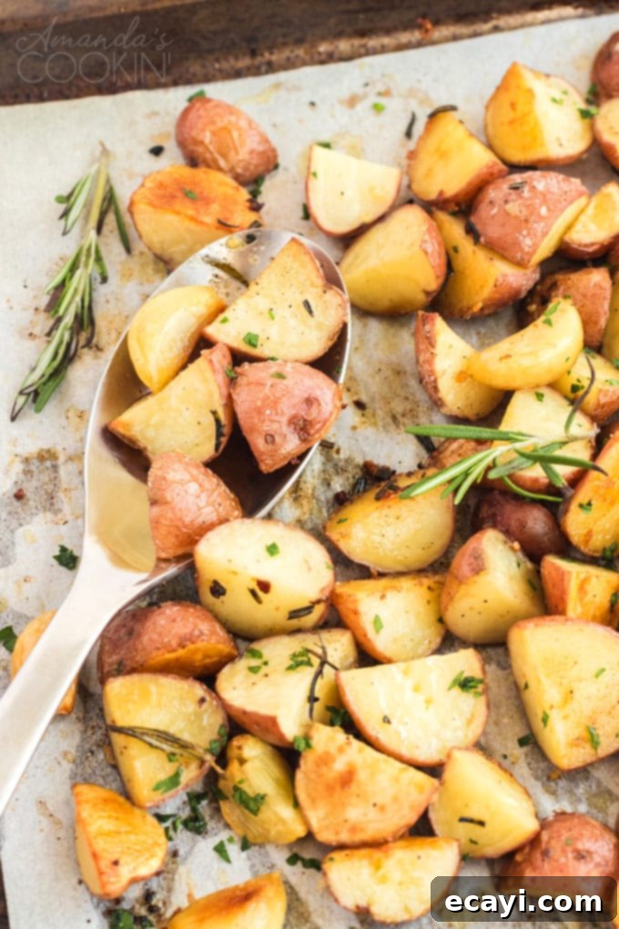 These golden roasted potatoes make the perfect Thanksgiving side dish. These potatoes are perfectly seasoned with rosemary and garlic! #thanksgiving #easter #holidaysides #holidaydish #easterdinner #dinnersides #sidedish #potatoes #garlic #christmasdinner roast potatoes on a baking pan with spoon