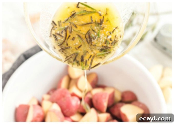 Aromatic Rosemary Garlic Potatoes 3 pouring melted butter mixture into a bowl of red potatoes