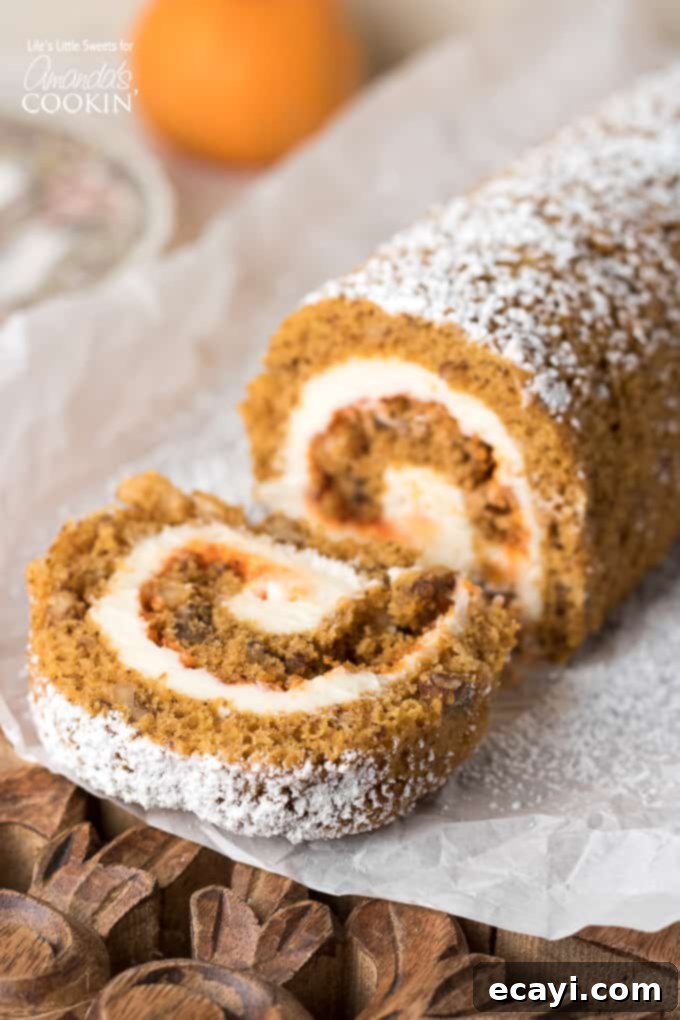 This Pumpkin Roll recipe is the perfect recipe to feature on the Thanksgiving dessert table! #pumpkinroll #pumpkincake #creamcheese #pumpkinrecipes #cake #thanksgivingdesserts #falldesserts A perfectly sliced pumpkin roll cake, showing its beautiful cream cheese swirl and dusted with powdered sugar, ready to be served on a white plate. This festive dessert is ideal for Thanksgiving.