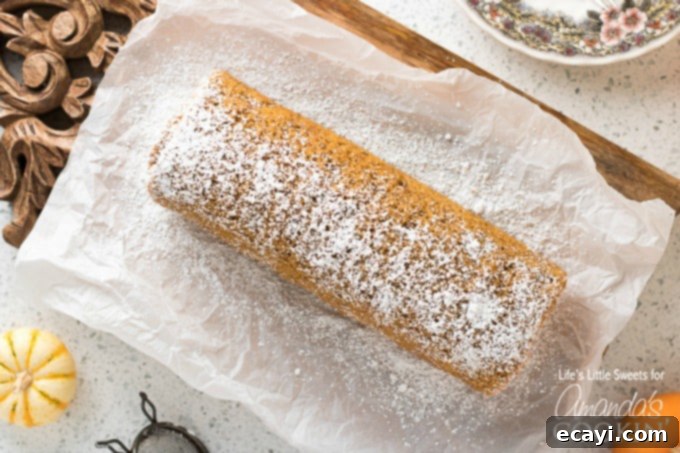 This Pumpkin Roll is a thin, moist pumpkin cake with or without walnuts, filled with a creamy frosting mixture and wrapped into a swirl of sweet heaven! Close-up of a pumpkin roll cake, generously dusted with confectioner's sugar, emphasizing its soft texture and inviting autumn glow.