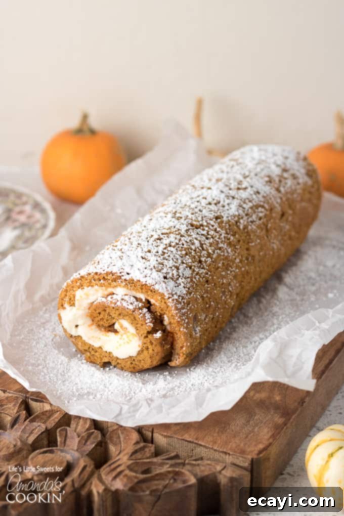 This Pumpkin Roll is a thin, moist pumpkin cake with or without walnuts, filled with a creamy frosting mixture and wrapped into a swirl of sweet heaven! A festive pumpkin roll cake, adorned with a light dusting of powdered sugar, presented beautifully on a wire rack, ready for slicing and serving as a seasonal delight.